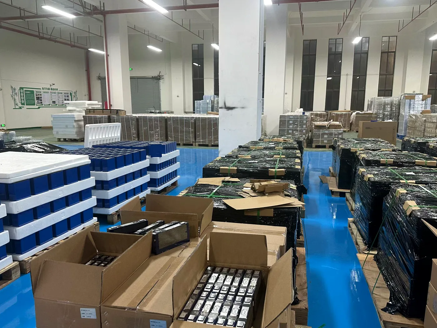 Battery workshop with cells, packed pallets, and project delivery preparation